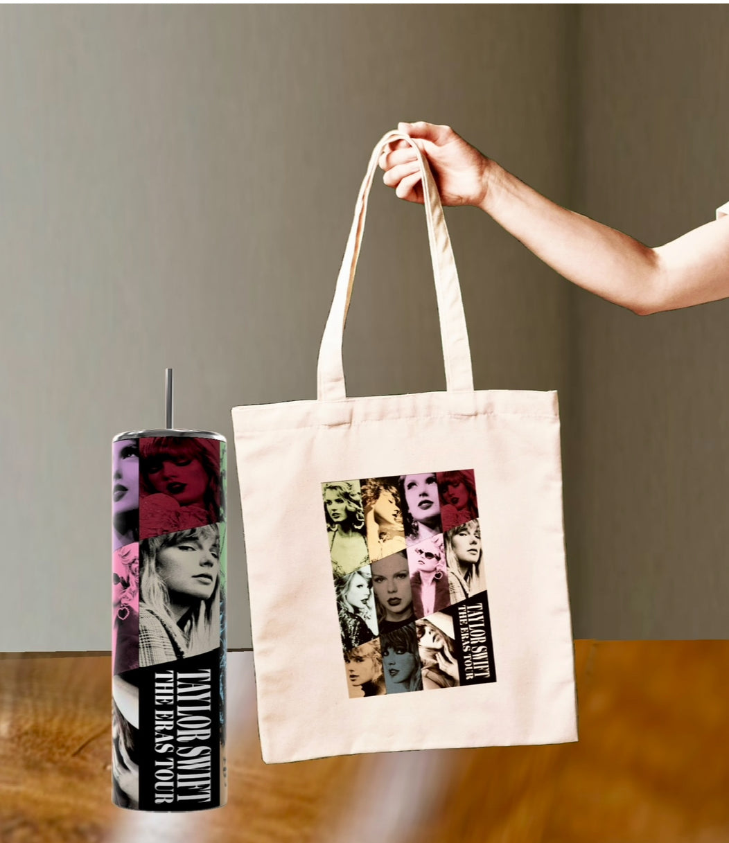 A hand holds a beige tote bag featuring colorful pop-art-style images of a person. Nearby, a tumbler cup on a wooden surface has a similar design with text that reads "TAYLOR SWIFT | THE ERAS TOUR.