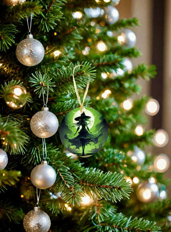 A close-up of a decorated Christmas tree with silver baubles and white lights features the special Wicked Witch Christmas Tree Ornament by Kreative Kreationz. This distinctive ornament showcases a sublimated design with the silhouette of a person set against a green, mystical background, adding an enchanting touch to your holiday decor.