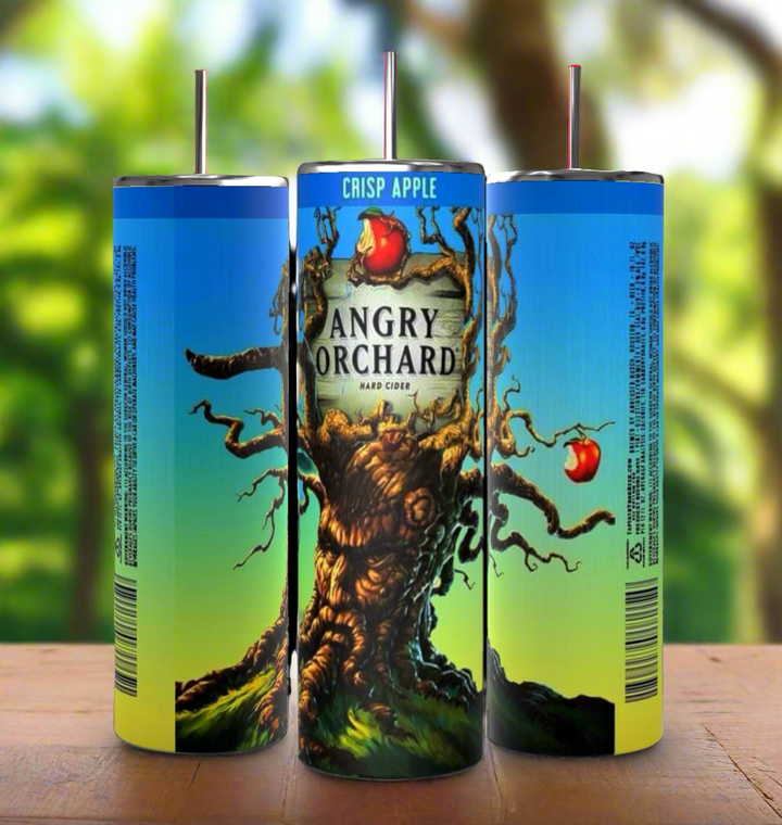 Three cans of Angry Orchard Crisp Apple Hard Cider are arranged with their labels showing. The central can features the Angry Orchard logo with an illustration of a gnarled tree with apples. The background is a blurred image of a sunny orchard, next to a Kreative Kreationz product: the Angry Orchard 20oz Tumbler boasting durable construction and 20 oz capacity.
