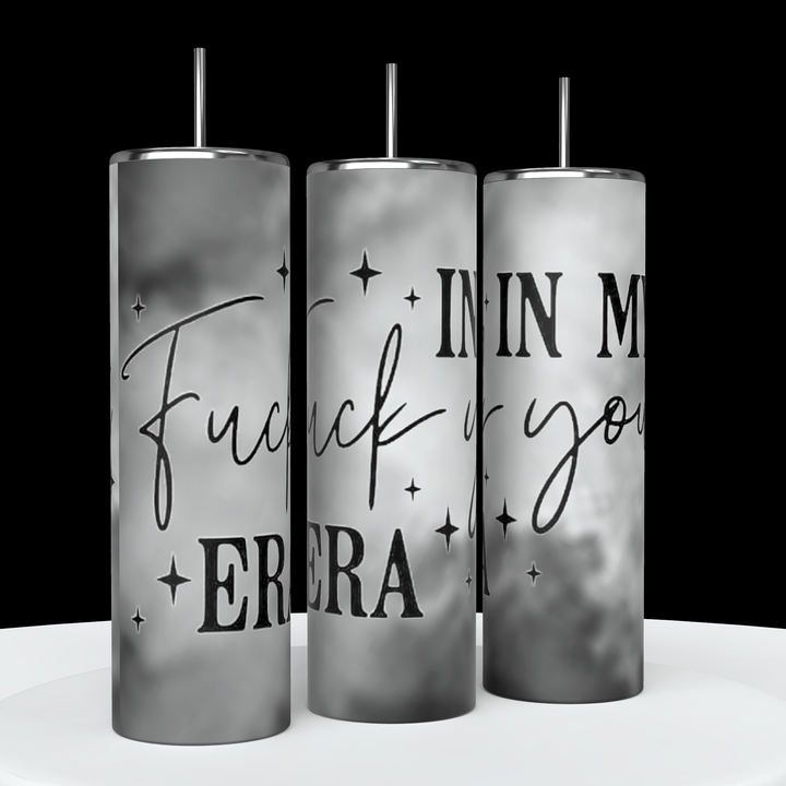 Three tall, cylindrical "In My Fuck You Era 20oz Tumblers" by Kreative Kreationz are displayed. Each tumbler features spill-proof lids and reusable black straws, with a gray and white gradient background. Bold text reading "Fuck you, I'm in my era" is prominently displayed, surrounded by small scattered stars.