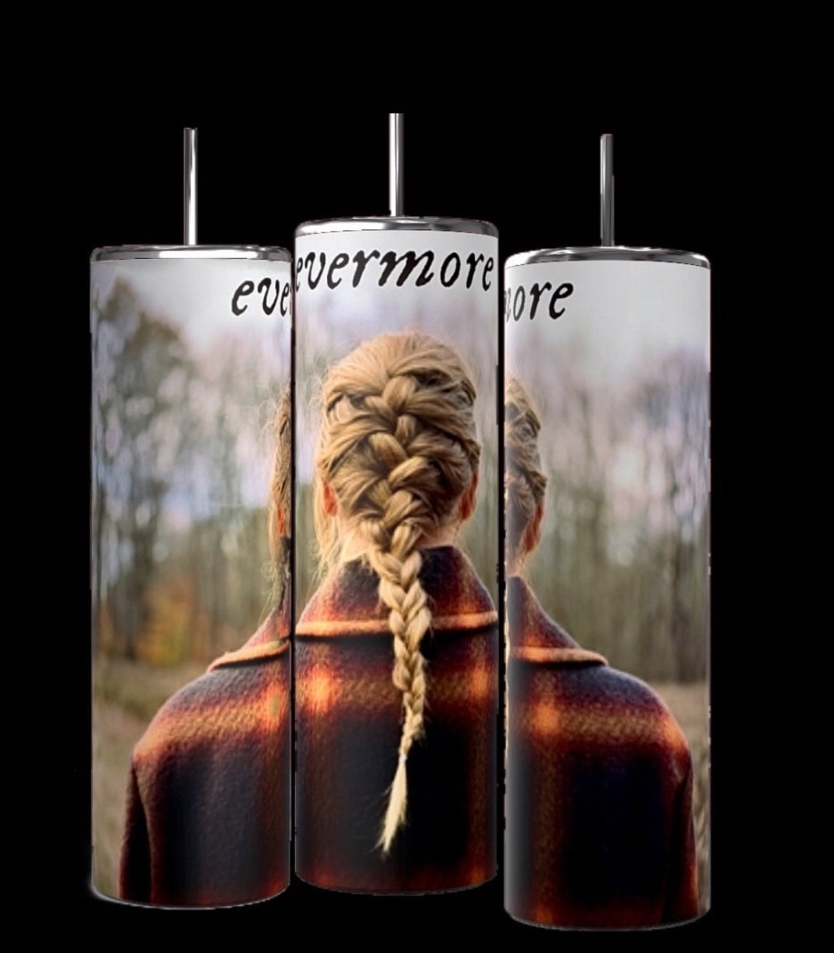 Three Evermore | Taylor Swift 20oz Skinny Tumblers by Kreative Kreationz with spill-proof lids are displayed on a wooden surface with a forest background. Each tumbler features an image of a person with a braided hairstyle facing away and the word "evermore" written at the top.