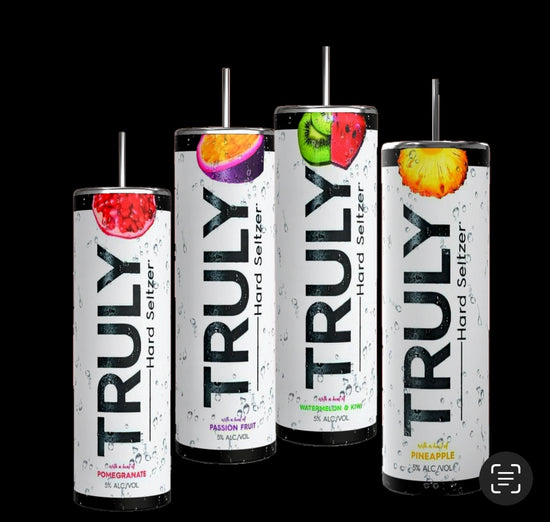 Four cans from the Truly Hard Seltzer 20oz Skinny Tumbler Collection by Kreative Kreationz are displayed on a wooden surface. The flavors showcased are pomegranate, passion fruit, pineapple, and another indistinguishable fruit. The sleek, tall cans feature refreshing water droplets on their design. Enhance your drinking experience with a reusable straw for an eco-friendly touch.