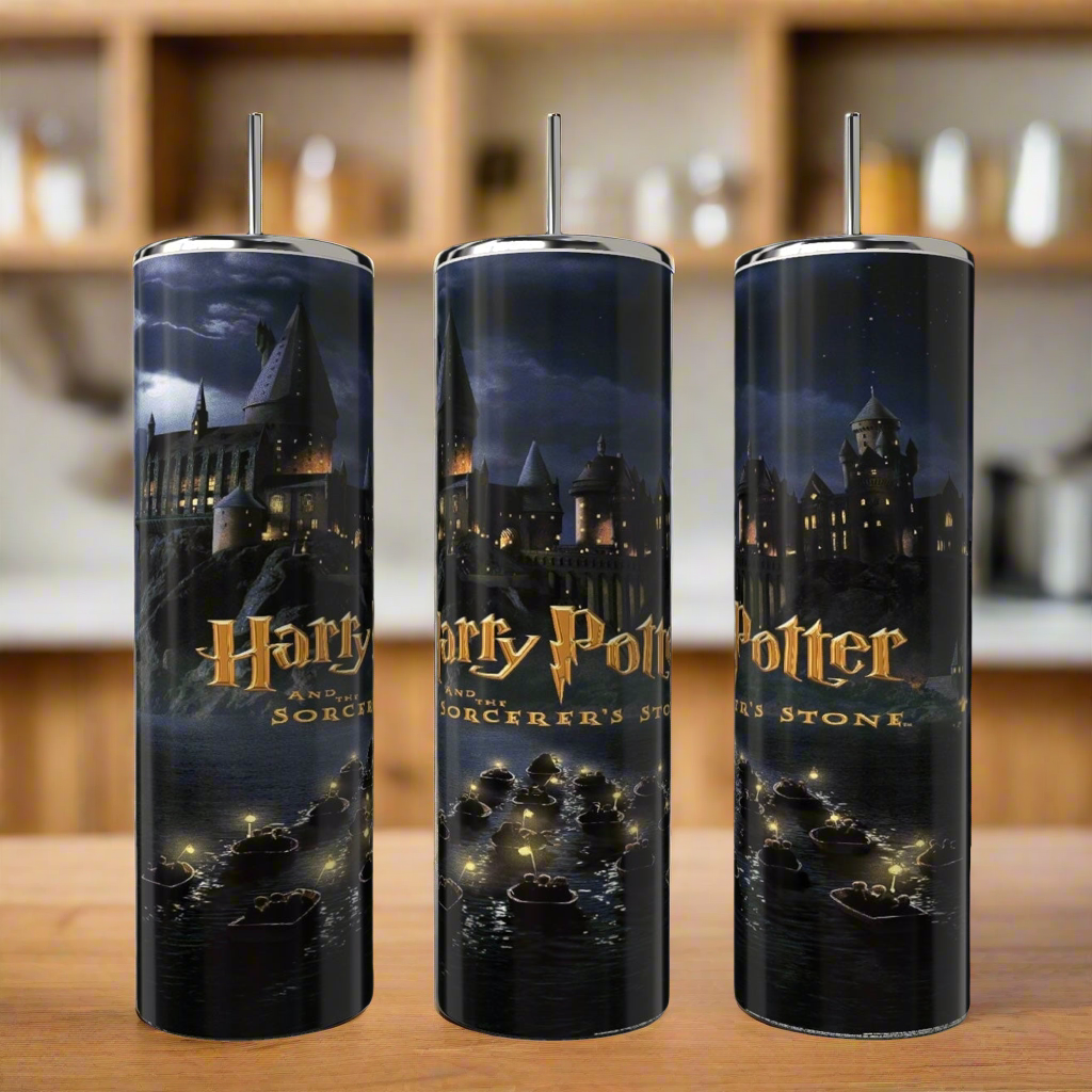 The Kreative Kreationz Harry Potter 20oz tall, cylindrical tumblers feature a Sorcerer's Stone design showing Hogwarts at night with boats on a lake and the title. These skinny tumblers are perfect for use with a reusable straw and are set on a wooden countertop.