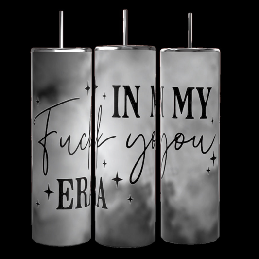 Three tall, cylindrical metal tumblers from Kreative Kreationz are displayed against a black background. The "In My Fu*k You Era" 20 oz tumblers feature reusable straws and a black and white smoky design with the text "IN MY Fuck you ERA" in a mix of bold and script fonts. Small stars are scattered around the text.