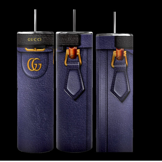 Three tall, cylindrical Gucci Diana-inspired purple tumblers from Kreative Kreationz, featuring a leather-like texture, gold Gucci logos, and black straws, stand on a cobblestone street. With durable construction and a 20 oz capacity, the focus remains on these stylish and luxurious cups against the softly blurred background.