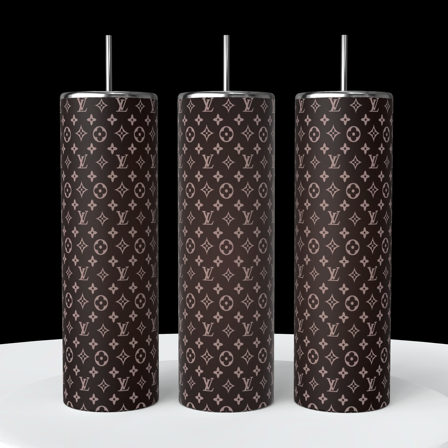 Three LV Ombre 20oz Skinny Tumblers from Kreative Kreationz, each featuring a dark background with a light pink luxury brand logo pattern and accompanied by silver straws, are elegantly positioned on a white surface against a black backdrop. These double-wall stainless steel tumblers add an upscale touch to any setting.