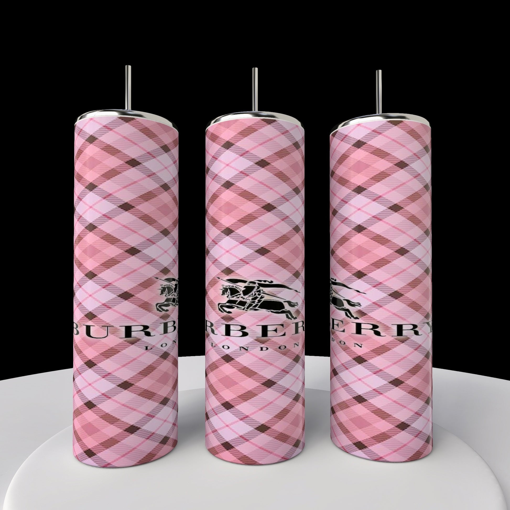 Three pink plaid hot water bottles with metal caps, featuring a black logo and "Burberry London" text stand upright on a white surface against a black backdrop. Their design mirrors the elegance of Kreative Kreationz's Burberry 20oz Skinny Tumbler, seamlessly fusing style with functionality.