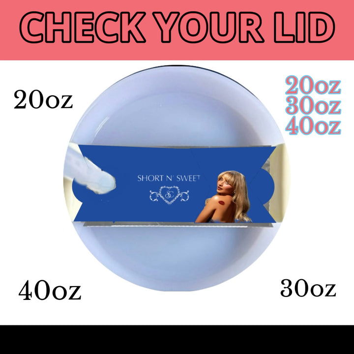 A white mug with a light blue button feature, covered by a lid. On the lid sits a blue, rectangular packaging featuring an image of a woman with blonde hair in a black outfit. The text on the packaging reads "SHOW 'N' SWEET." Crafted from premium materials, it resembles the Sabrina Carpenter Short & Sweet Stanley Lid Plate/Topper by Kreative Kreationz in quality.