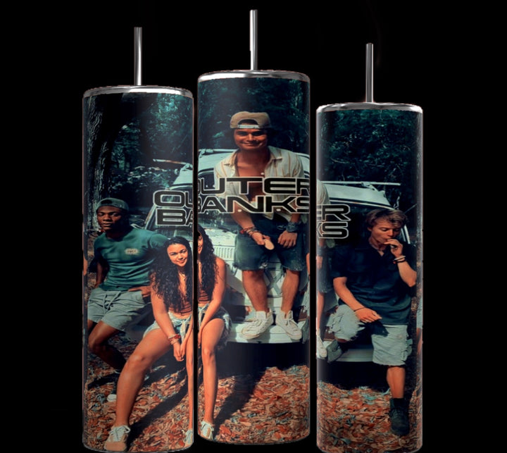 Three cylindrical tumblers, reminiscent of the popular Stanley design, are shown, each featuring a personalized collage of characters from the TV show "Outer Banks." The tumblers display the show's logo, character photos, and scenic backgrounds. They are arranged side by side on a white surface against a black backdrop.