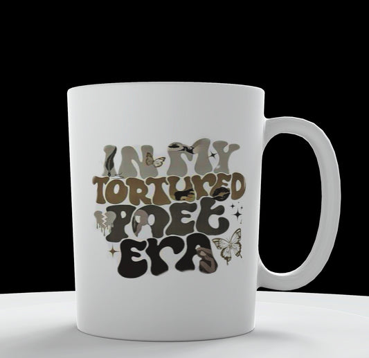 A distinctive design from Kreative Kreationz, the IN MY TTPD ERA Ceramic Mug boasts the text "IN MY TORTURED POET ERA" in a whimsical, artistic font. The letters are adorned with various patterns, including butterfly designs in earthy tones. This white mug is perfect for any Taylor Swift fan and is showcased on a white platform against a black background.