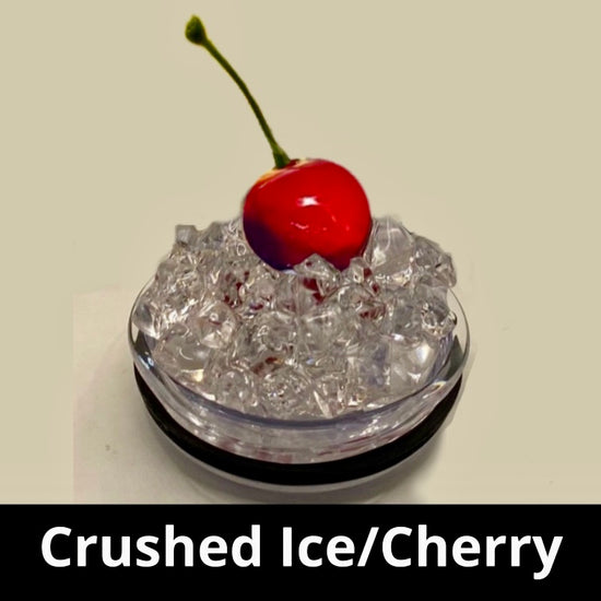 A slice of lime sits atop a pile of crushed ice, elegantly displayed on a small, round, clear platform against a beige background that accentuates the lime and ice. A black strip at the bottom features white text reading 