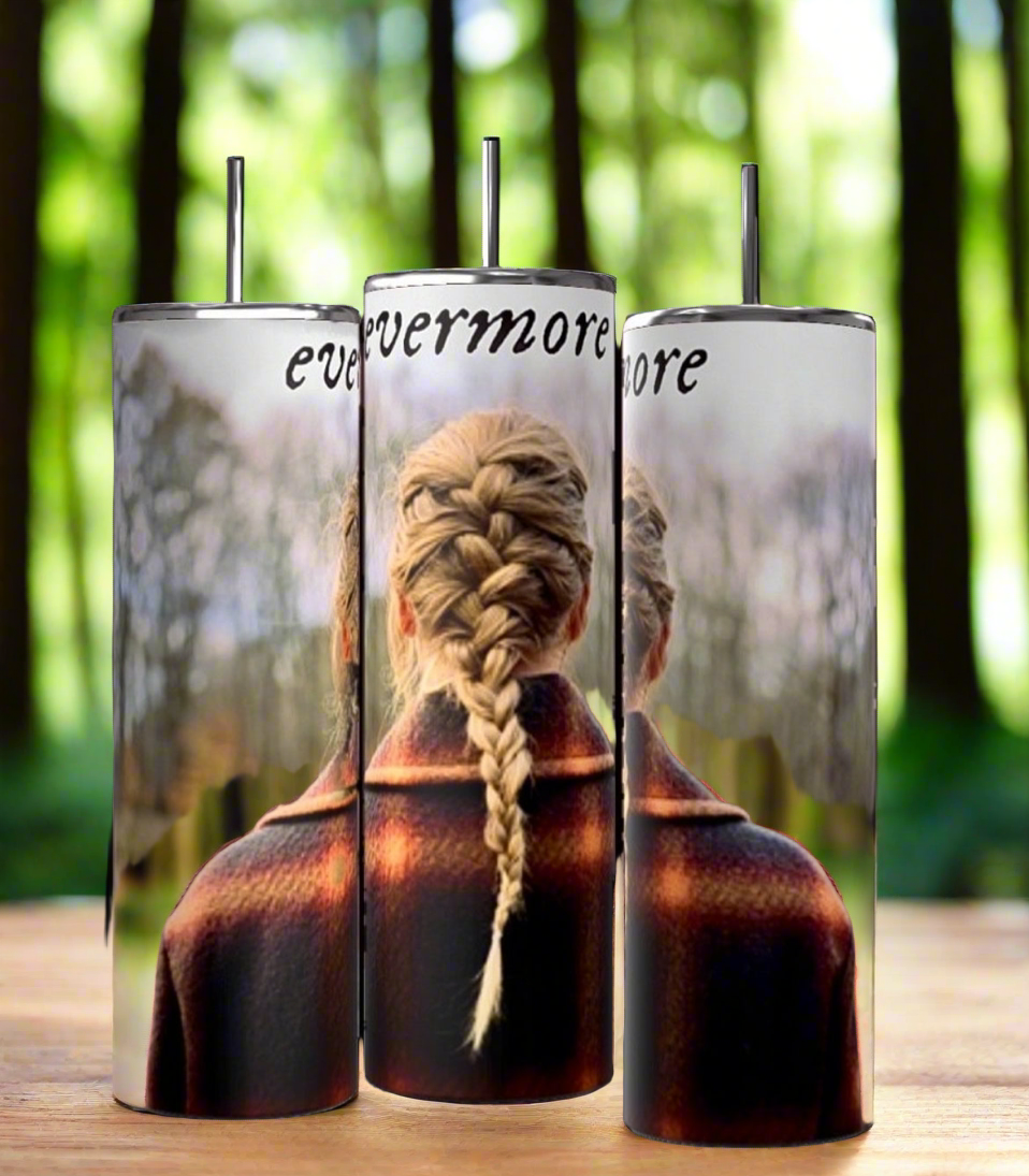 Three Evermore | Taylor Swift 20oz Skinny Tumblers by Kreative Kreationz with spill-proof lids are displayed on a wooden surface with a forest background. Each tumbler features an image of a person with a braided hairstyle facing away and the word "evermore" written at the top.