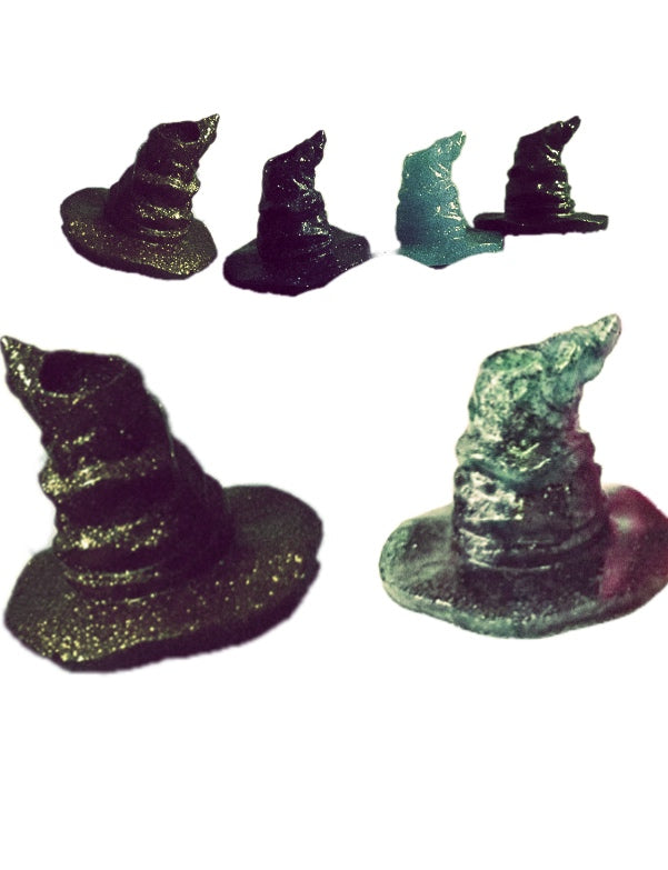 A Harry Potter Wizard | Witch Hat straw decoration from Kreative Kreationz stands upright, securely held in place by a mound of golden, glittery clay on a blue plastic surface. The background features lush green foliage and a red flower. The timestamp and battery indicator suggest the photo was taken on a mobile phone.