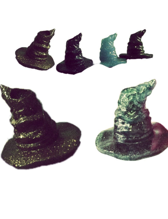 A Harry Potter Wizard | Witch Hat straw decoration from Kreative Kreationz stands upright, securely held in place by a mound of golden, glittery clay on a blue plastic surface. The background features lush green foliage and a red flower. The timestamp and battery indicator suggest the photo was taken on a mobile phone.