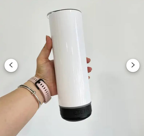 A hand holding a smartphone is shown to the left of a tall, cylindrical, white Kreative Kreationz Customized 20oz Bluetooth Tumbler. To the right of the tumbler, five small circular portable speakers in pink, blue, dark gray, black, and light gray are depicted. Musical notes are shown in the background.