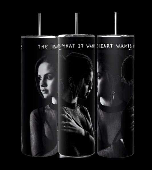 The Selena Gomez The Heart Wants What It Wants 20oz Stainless Steel Tumblers by Kreative Kreationz feature monochrome images of a young woman in contemplative poses against a dark background. The phrase "THE HEART WANTS WHAT IT WANTS" is partially visible across the top of each tumbler, and each has a 20 oz capacity.