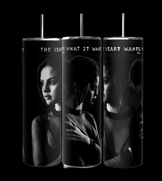 The Selena Gomez The Heart Wants What It Wants 20oz Stainless Steel Tumblers by Kreative Kreationz feature monochrome images of a young woman in contemplative poses against a dark background. The phrase 