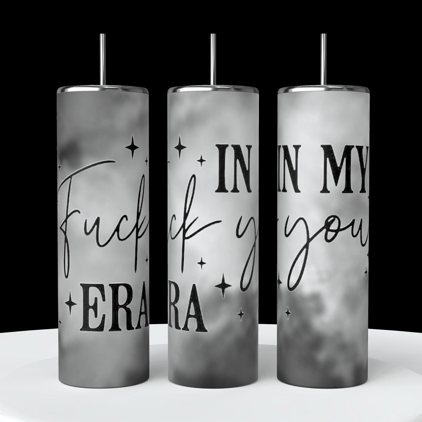 Three tall, cylindrical "In My Fuck You Era 20oz Tumblers" by Kreative Kreationz are displayed. Each tumbler features spill-proof lids and reusable black straws, with a gray and white gradient background. Bold text reading "Fuck you, I'm in my era" is prominently displayed, surrounded by small scattered stars.