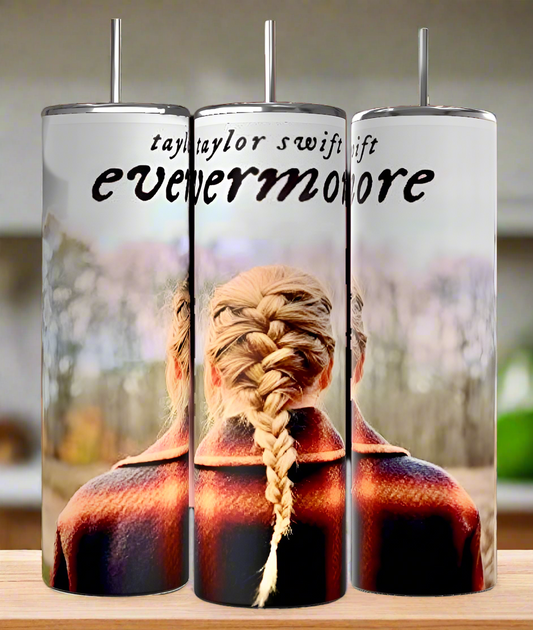 The Kreative Kreationz Evermore Taylor Swift 20oz Skinny Tumbler features the "evermore" album cover with a braided hairstyle and plaid coat against blurred trees. It includes a reusable straw and spill-proof lid, ideal for fans on the move. Text: "Taylor Swift evermore.