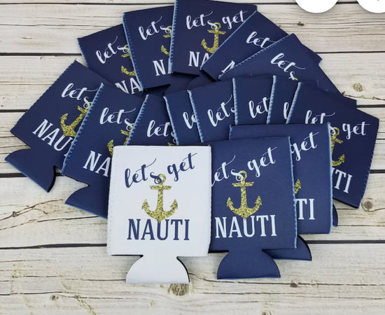 A set of Nautical Beach Theme 6-Pack Customizable Koozies from Kreative Kreationz is scattered on a wooden surface. These navy blue and white coolers are adorned with a gold anchor design and the phrase 