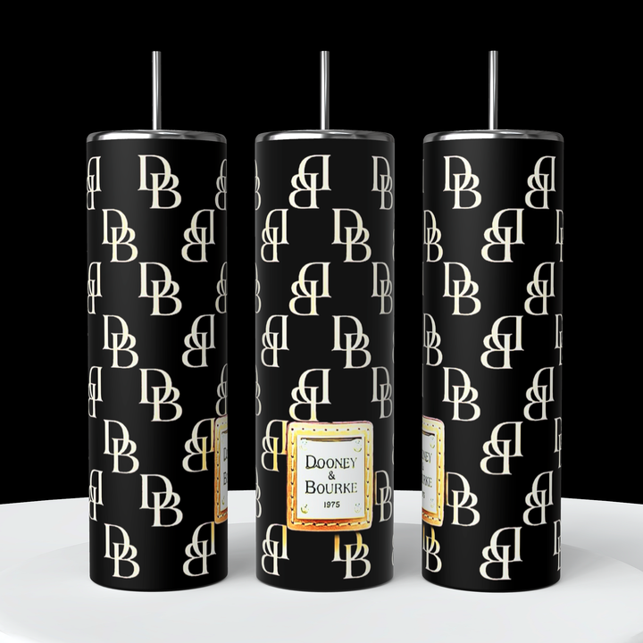 A stylish Dooney and Bourke - Black 20oz Tumbler by Kreative Kreationz is shown, featuring a black design with repeating white "DB" initials. The center showcases a gold-bordered label that reads "Dooney & Bourke 1975" in black. This tumbler includes double-wall insulation and comes with a reusable silver metal straw that fits at the top.