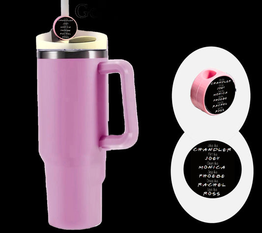 A tall pink insulated travel mug with a handle features the Friends Straw Topper by Kreative Kreationz—a personalized silicone round straw topper. Engraved names from the TV show "Friends" are on the lid, highlighted against a black backdrop for an elegant display.