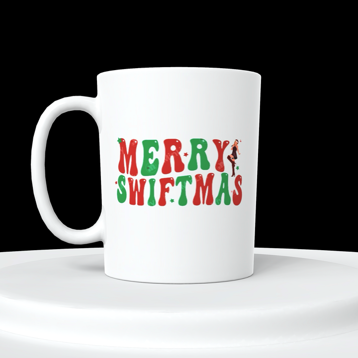 The Kreative Kreationz Merry Swiftmas Taylor Swift Ceramic Mug is a white ceramic mug featuring the phrase "Merry Swiftmas" adorned in red and green festive letters. Each letter is decorated with small Christmas-themed illustrations, and the "Y" showcases a silhouette of Taylor Swift dancing. This Eras mug is ideal for fans and looks elegant on any white surface.