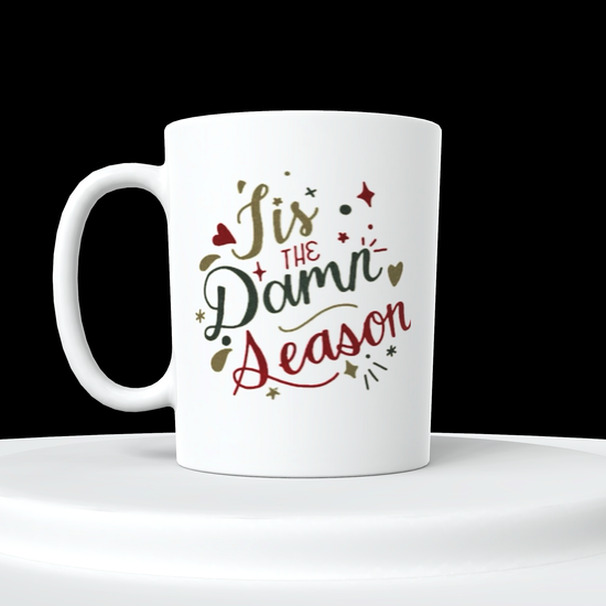 The Tis The Damn Season Taylor Swift Ceramic Mug by Kreative Kreationz features holiday-themed text reading 