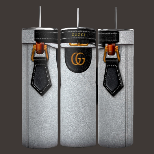 Introducing the GUCCI Purse Inspired 20oz Tumbler by Kreative Kreationz: This elegant set of three cylindrical silver tumblers showcases designs inspired by a GUCCI designer purse. Featuring black leather strap motifs and the famous Gucci logo with striking gold and black details, each tumbler is crafted for durability and comes with a metal straw on top, making them stand out beautifully against any dark backdrop.