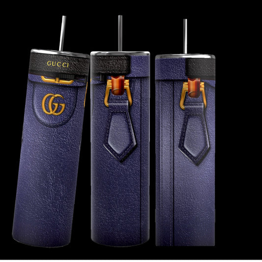 Three tall, cylindrical Gucci Diana-inspired purple tumblers from Kreative Kreationz, featuring a leather-like texture, gold Gucci logos, and black straws, stand on a cobblestone street. With durable construction and a 20 oz capacity, the focus remains on these stylish and luxurious cups against the softly blurred background.