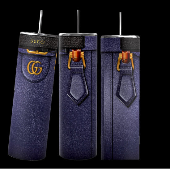 Three tall, cylindrical Gucci Diana-inspired purple tumblers from Kreative Kreationz, featuring a leather-like texture, gold Gucci logos, and black straws, stand on a cobblestone street. With durable construction and a 20 oz capacity, the focus remains on these stylish and luxurious cups against the softly blurred background.