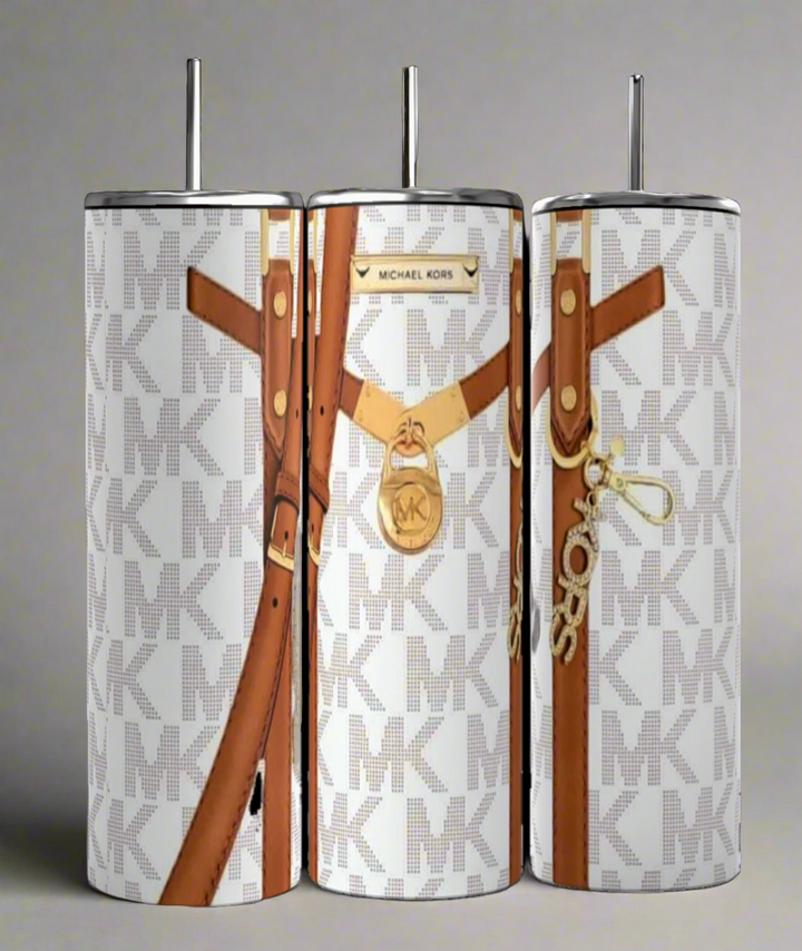 Three insulated, handmade Kreative Kreationz Michael Kors Design Inspired White and Brown 20oz Tumblers each boast a 20 oz capacity and an abstract design. Each tumbler features a white background with light gray "MK" initials, accented by brown belt graphics and gold-colored charms like the iconic Michael Kors logo. A city street is blurred in the background.