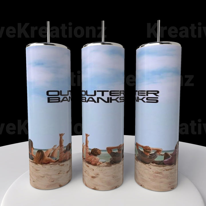 Three Outer Banks OBX 20oz Tumblers by Kreative Kreationz, featuring images of beach relaxation with blue skies and sands, are displayed on a circular platform. Each tumbler includes a spill-proof lid and straw.