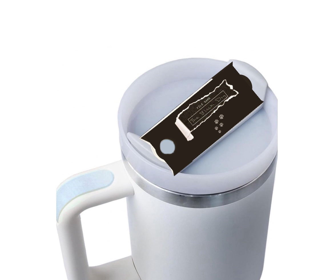 A white mug with a light blue handle is shown against a plain background. On top of the Kreative Kreationz Black Dog lid Plate/Topper, which fits 20, 30, and 40 oz Stanley cups, is a partially unwrapped chocolate bar with a black wrapper.