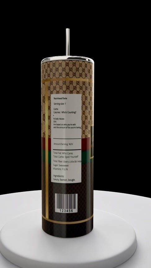 A tall, luxury-patterned Gucci 20oz Skinny Tumbler by Kreative Kreationz on a white pedestal evokes elegance. The sleek design, metallic top, and playful text mirror fashion-forward themes akin to FENDI.