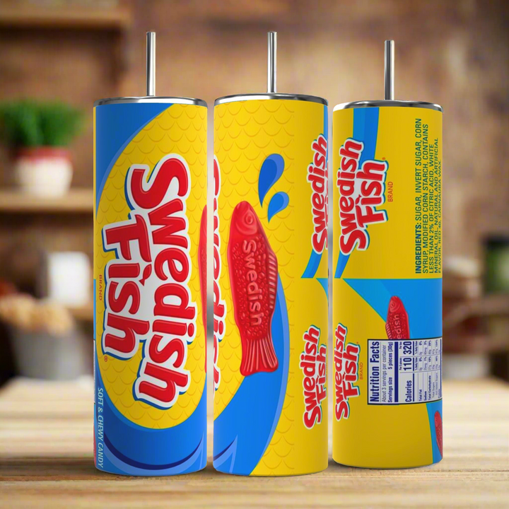 Three cylindrical Swedish Fish 20oz Stainless Steel Skinny Tumblers by Kreative Kreationz are displayed, each featuring a vibrant candy design. Predominantly blue and yellow with red fish graphics and the text "Swedish Fish," one tumbler comes with nutritional facts on the back. All have metal straws, making them perfect stainless steel tumblers for any occasion.