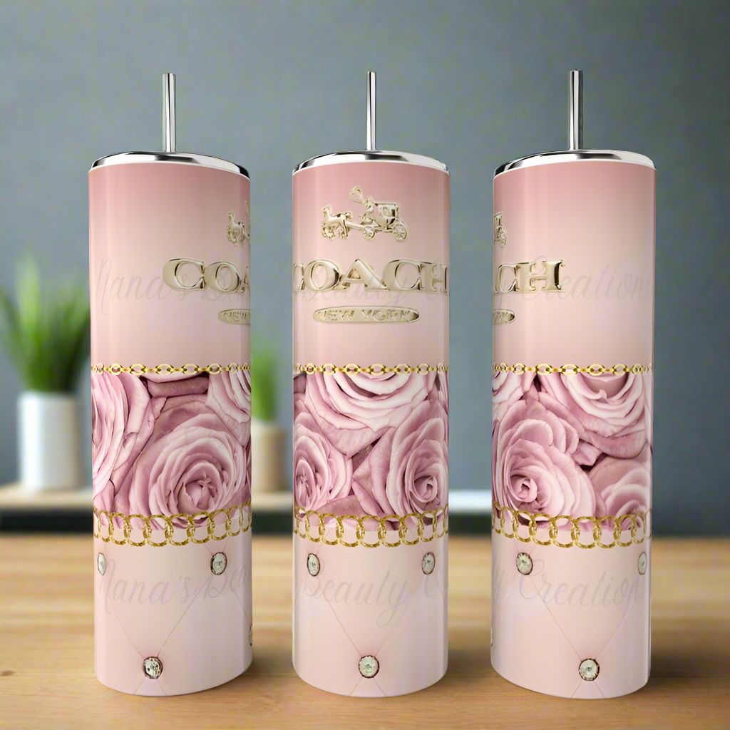 Three Coach | Floral 20oz Skinny Tumblers by Kreative Kreationz, featuring pink roses and gold chain accents on a luxury design with silver lids, are showcased on a wooden surface. The blurred indoor background highlights the elegance of this eco-friendly drinkware.