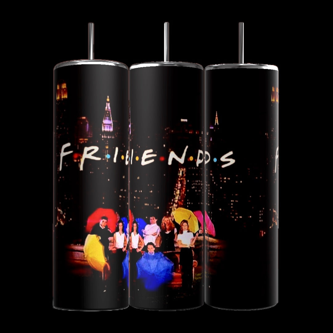 Three black Friends Tv Show 20oz Tumblers-Umbrella by Kreative Kreationz are decorated with the "Friends" TV show logo and a nighttime cityscape. A colorful image featuring six people sitting with umbrellas and wearing various colored jackets is displayed on the bottom of the tumblers, split across their surface.