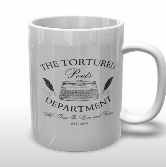 A white ceramic mug from Kreative Kreationz, named "The Tortured Poets Department | TTPD Ceramic Mug," features the text "The Tortured Poets Department" and an illustration of a vintage typewriter in the center. Below the illustration, it reads "All's Fair in Love and Poetry" and "Est. 2024." The mug is placed on a wooden surface with a plant in the background, making it perfect for any Taylor Swift fan.