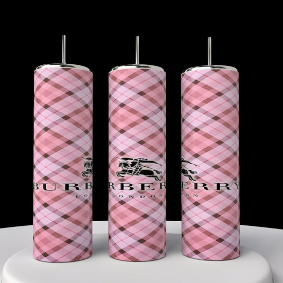 Three Burberry 20oz Skinny Tumblers by Kreative Kreationz, with pink plaid patterns and silver tops, are neatly arranged. Each includes a logo and text on the front, displayed on a white circular surface against a black background, highlighting their seamless design.