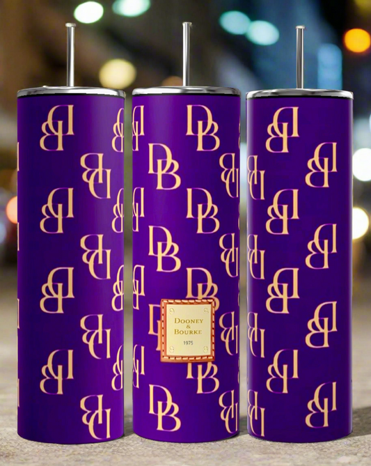 Three D&B -Purple 20oz Tumblers from Kreative Kreationz, each adorned with a gold "DB" monogram pattern and a central label that reads "Dooney & Bourke 1975," are displayed in a row. Their sublimated design showcases a background of blurred city lights, enhancing their allure.