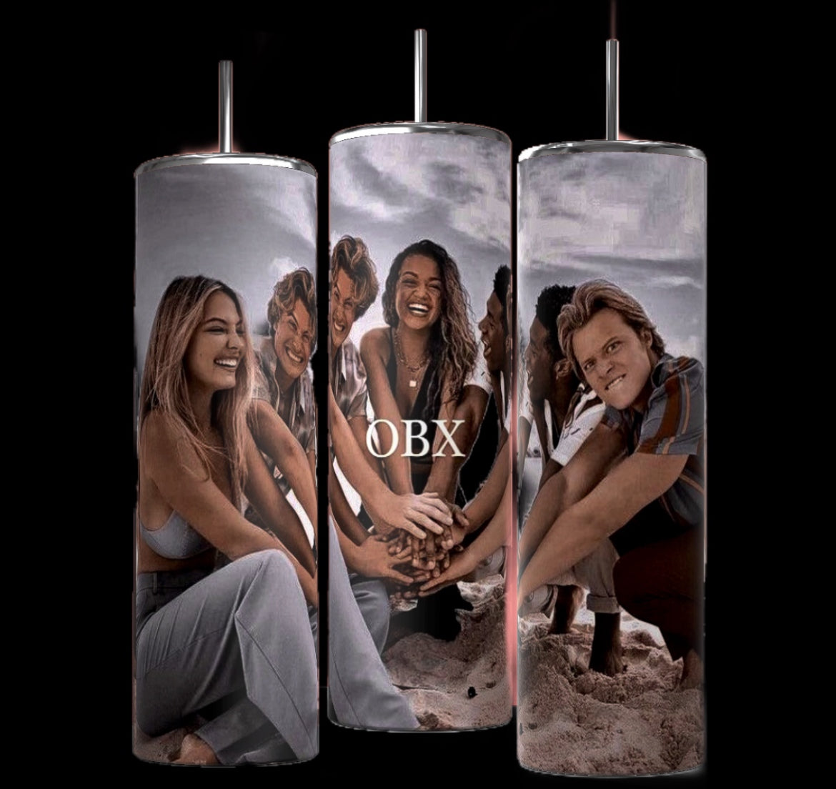 Three cylindrical tumblers, reminiscent of the popular Stanley design, are shown, each featuring a personalized collage of characters from the TV show "Outer Banks." The tumblers display the show's logo, character photos, and scenic backgrounds. They are arranged side by side on a white surface against a black backdrop.