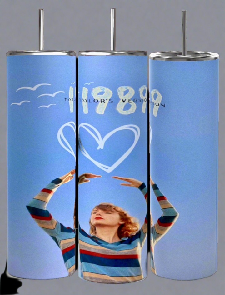 Discover the allure of the Kreative Kreationz 1989 20oz Tumbler. It features a person in a striped sweater with arms raised against a blue background, text saying "1989 Taylor's Version," accented with white birds and a heart drawing. The spill-proof lid makes it ideal for your on-the-go escapades.