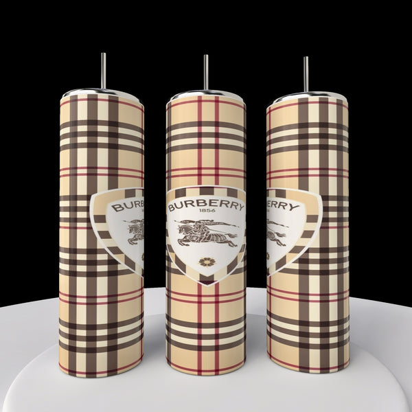 Three tall candles featuring the classic Burberry plaid pattern with logo, reminiscent of a Kreative Kreationz's Burberry 20oz Skinny Tumbler, stand side by side on a round white platform against a black background, adding elegance and style to any setting.