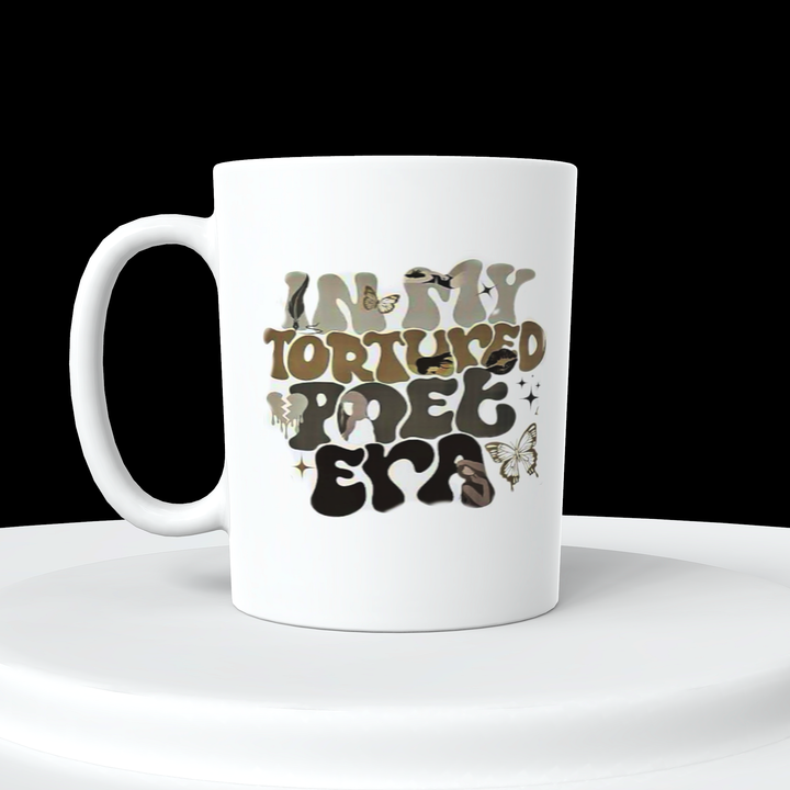 A distinctive design from Kreative Kreationz, the IN MY TTPD ERA Ceramic Mug boasts the text "IN MY TORTURED POET ERA" in a whimsical, artistic font. The letters are adorned with various patterns, including butterfly designs in earthy tones. This white mug is perfect for any Taylor Swift fan and is showcased on a white platform against a black background.