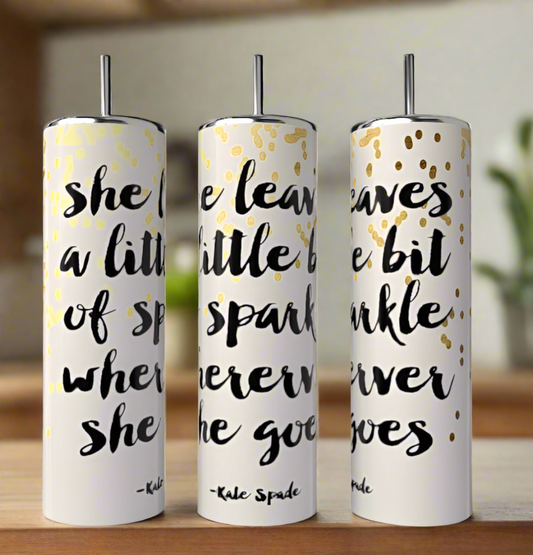 Three tall, decorative white candles feature a bold black quote: "she leaves a little bit of sparkle wherever she goes – Kate Spade" with gold dots, perfectly paired with the eco-friendly Kate Spade Sparkle 20oz Skinny Tumbler by Kreative Kreationz. They charm against a blurred home background.