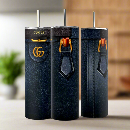 Three tall, blue leather-like Gucci Diana Purse 20oz Tumblers by Kreative Kreationz, adorned with gold accents, logos, vertical stitching, and red clasps, showcase their durable construction on a light surface against a blurred background.