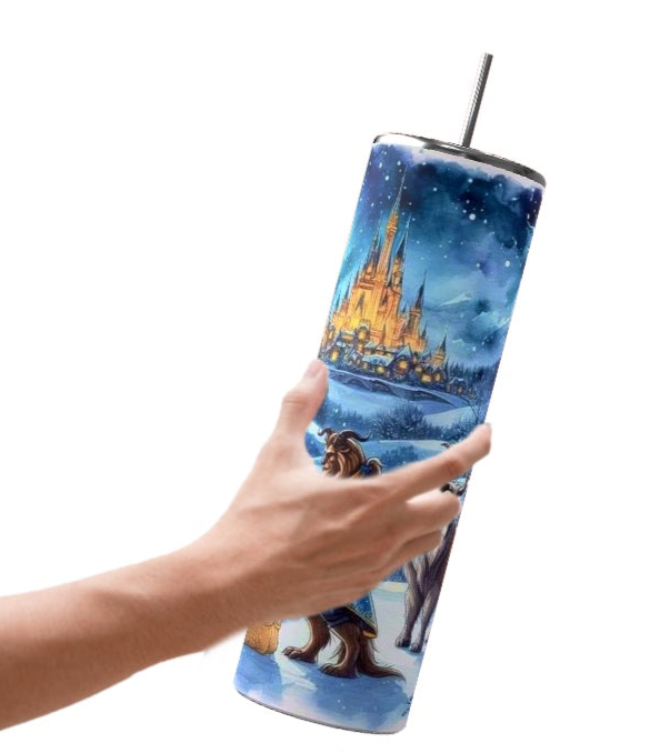 A person's hand holds the Kreative Kreationz Beauty & The Beast 20oz Tumbler, showcasing a fairy tale castle and characters in a snowy landscape. The vibrant, colorful design comes equipped with a spill-proof lid and straw for easy use.