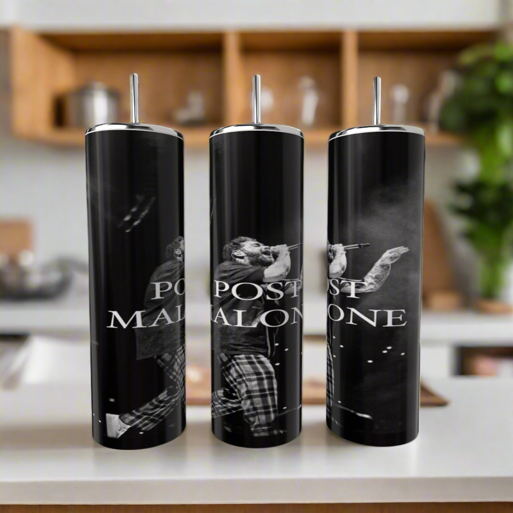 Three luxury-inspired Posty tumblers from Kreative Kreationz, adorned with images of Post Malone and the text "POST MALONE," are elegantly showcased on a kitchen counter. The sleek black finish pairs perfectly with the stainless steel look, framed by stylish cabinets and lush greenery.