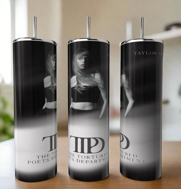 Three tall, cylindrical skinny tumblers from Kreative Kreationz feature a black-and-white image of a woman with long hair and the text "The Tortured Poets Department" and "TTPD" against a blurred background, positioned on a table.